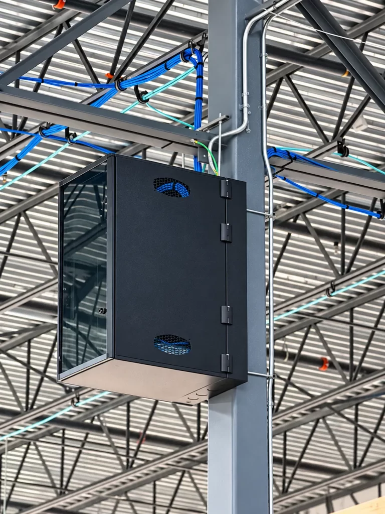 Network enclosure mounted on a steel column with overhead cabling in a warehouse