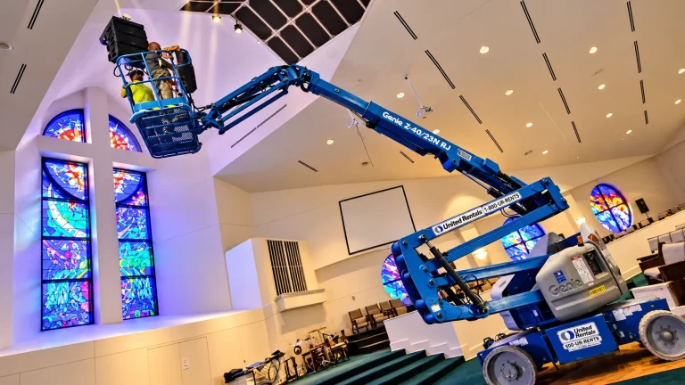 SpaceCenter Systems technicians installing line-array speakers in a church sanctuary