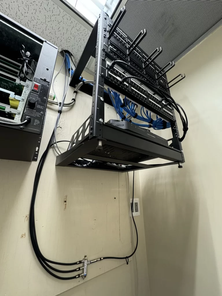 Wall-mounted rack with dressed blue Cat6 cabling installed by SpaceCenter Systems